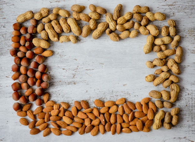 Assortimento di noci su uno sfondo in legno. Il cibo mescola il fondo, la vista superiore, lo spazio della copia, insegna