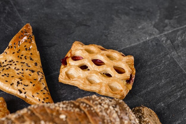 Assortimento di pane appena sfornato su sfondo scuro Panini di pane bianco e di segale con copia posto