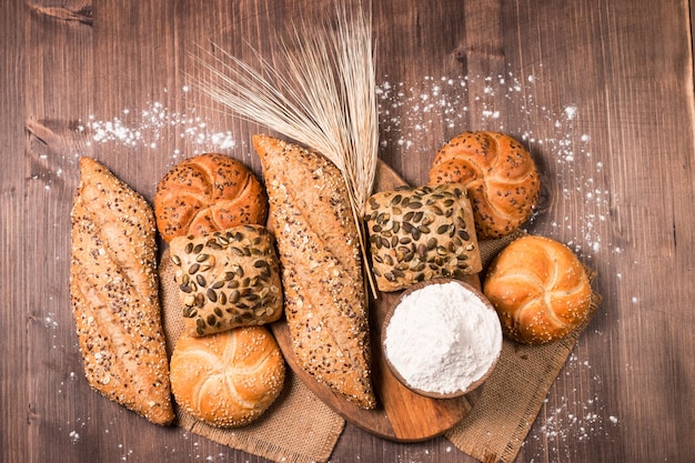 Assortimento di pane cotto con semi su uno sfondo di tavolo in legno. Forno. Concetto di sicurezza alimentare.