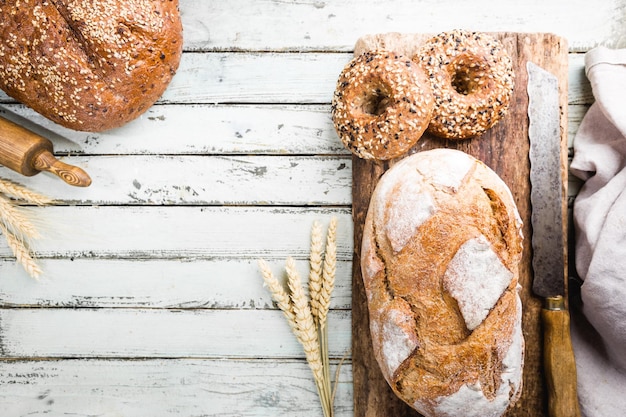 Assortimento di pane e panini appena sfornati su sfondo di tavolo in legno, vista dall'alto