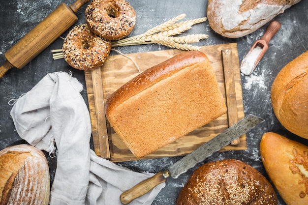 Assortimento di pane e panini appena sfornati su sfondo nero, vista dall'alto