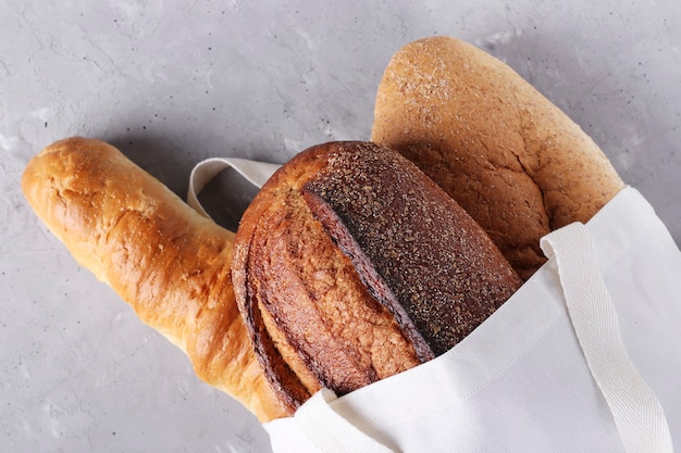 Assortimento di pane fresco in una shopping bag in tessuto di cotone su un cemento grigio.