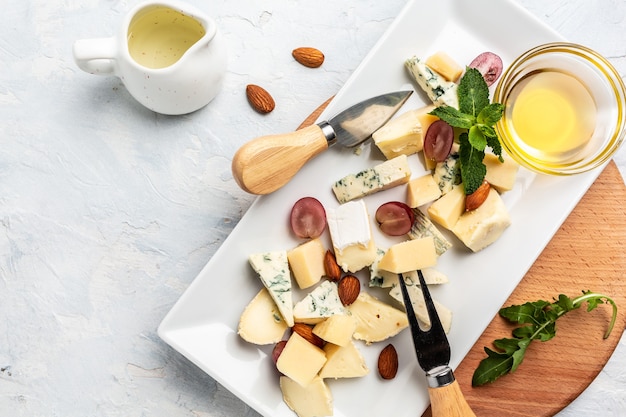 Assortimento di piatti di formaggi di vari tipi di formaggio con uva, miele e noci, vista dall'alto.