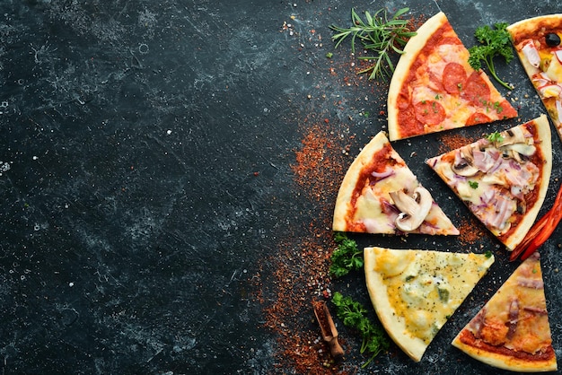 Assortimento di pizza a fette su sfondo di pietra nera Vista dall'alto spazio libero per il testo Stile rustico