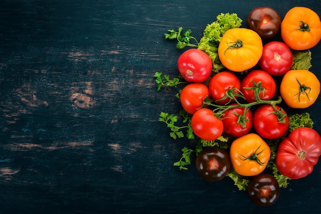 Assortimento di pomodori freschi colorati su sfondo di legno nero Vista dall'alto Spazio di copia