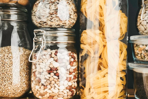 Assortimento di prodotti a base di cereali e pasta in contenitori di vetro su tavola di legno Cucina sana, mangiare pulito, concetto di zero rifiuti Cibo dietetico equilibrato