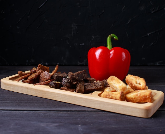 Assortimento di snack malsani alla birra in una ciotola su sfondo di legno scuro vista dall'alto