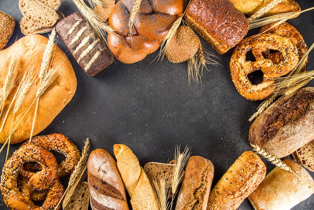 Assortimento di vari deliziosi pane appena sfornato, su sfondo di cemento nero vista dall'alto spazio copia