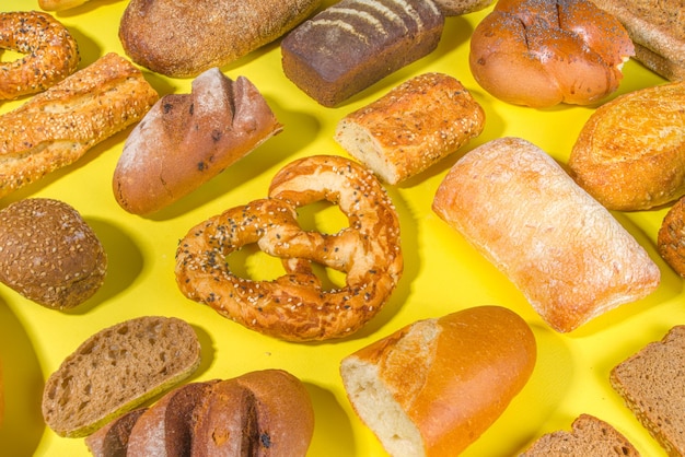 Assortimento di vari deliziosi pane appena sfornato, sulla superficie luminosa alla moda vista dall'alto lo spazio della copia, modello su giallo