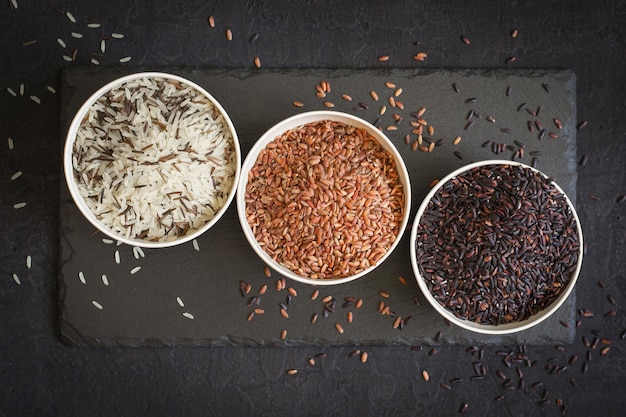 Assortimento di varietà di riso gourmet in ciotole Su sfondo nero. Vista dall'alto.