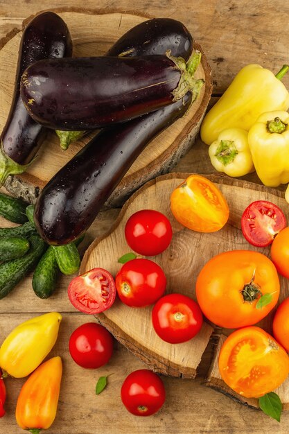 Assortimento di verdure fresche su un fondo di legno. Pomodori maturi, melanzane, cetrioli e peperoni, vista dall'alto