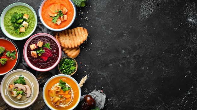 Assortimento di zuppe di crema di verdure colorate Alimenti dietetici Su uno sfondo di pietra nera Vista dall'alto Spazio per la copia gratuito