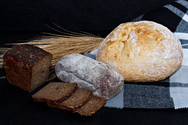 Assortiti diversi tipi di pane bianco e nero su uno sfondo nero.