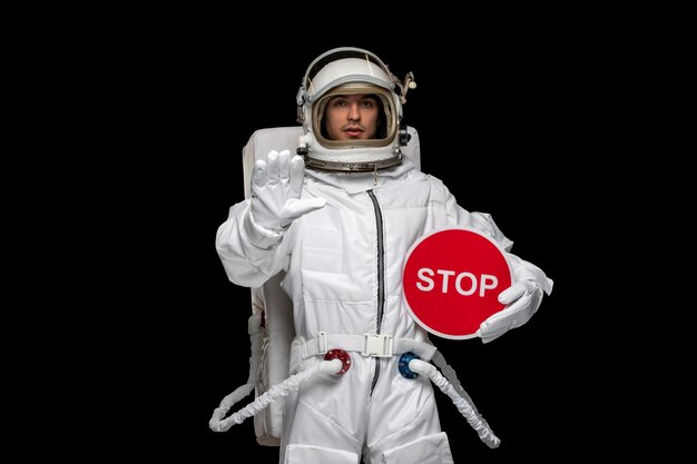 Astronauta astronauta diurno in casco tuta spaziale che tiene il segnale di stop rosso e mostra il gesto di stop