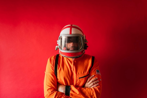 Astronauta con casco e tuta spaziale arancione su sfondo rosso