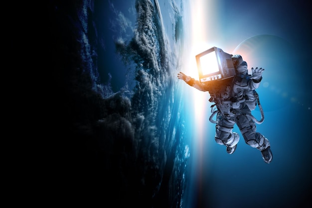 Astronauta con la testa della TV vintage alla passeggiata spaziale sull'orbita del pianeta. Tecnica mista.