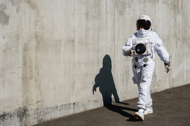 Astronauta futuristico in un casco contro le pareti grigie. Fantastico costume cosmico.