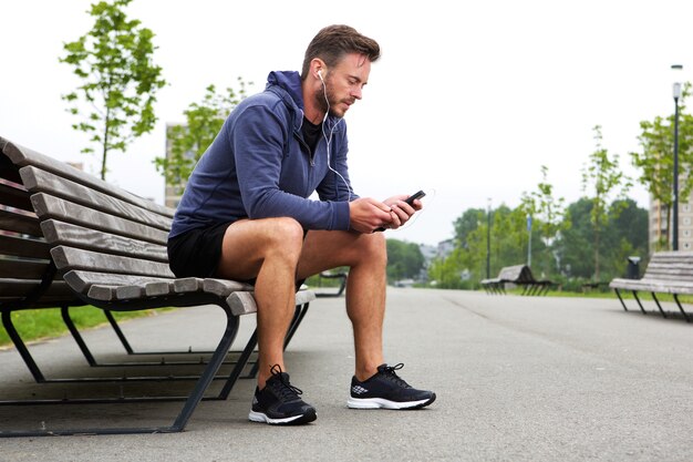 Atleta anziano seduto ascoltando musica fuori