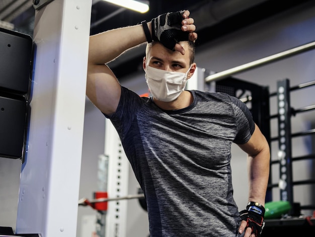 Atleta che si allena in palestra durante la pandemia indossando una maschera protettiva