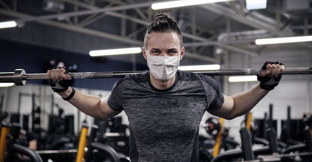 Atleta che si allena in palestra durante la pandemia indossando una maschera protettiva