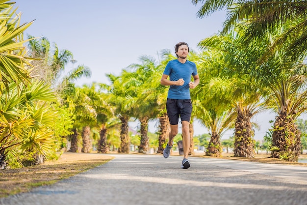 Atleta corridore in esecuzione al parco tropicale uomo fitness alba jogging allenamento concetto di benessere