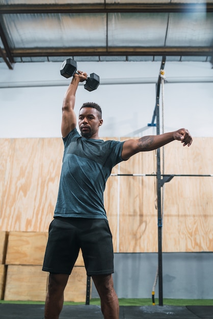 Atleta di Crossfit che fa esercizio con la testa di legno.