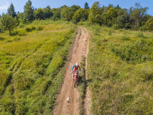 Atleta di enduro su una veduta aerea di una pista sterrata estiva