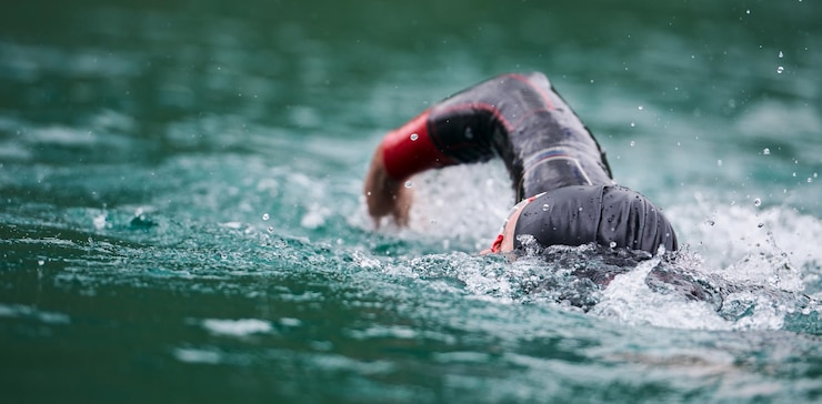 Foto atleta di triathlon che nuota sul lago indossando una tuta da bagno