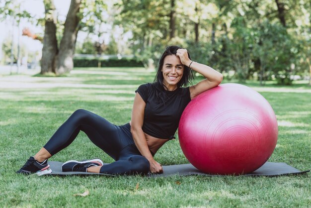 Atleta donna con una grande palla fitness si allena nel parco