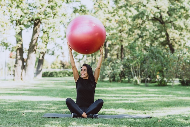 Atleta donna con una grande palla fitness si allena nel parco