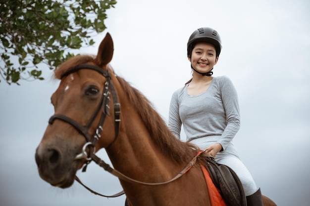 Atleta equestre di bella donna che pratica l'equitazione su sfondo all'aperto