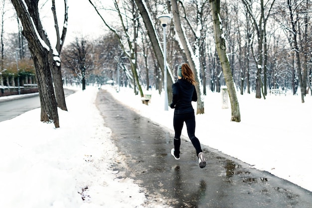 Atleta femminile che fa jogging nel parco in inverno