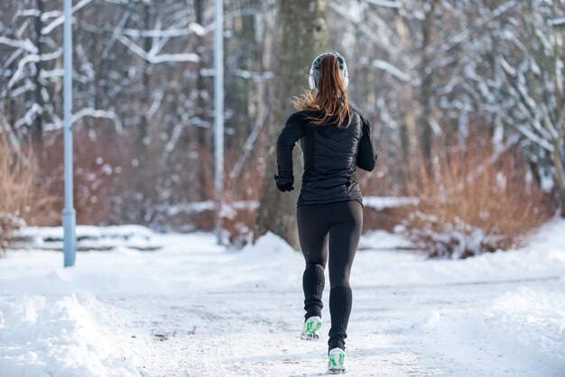 Atleta femminile che pareggia sul parco il giorno di inverno nel parco