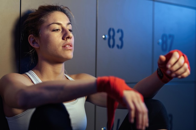 Atleta femminile che si siede nello spogliatoio dopo l'allenamento sportivo e si sente stanco