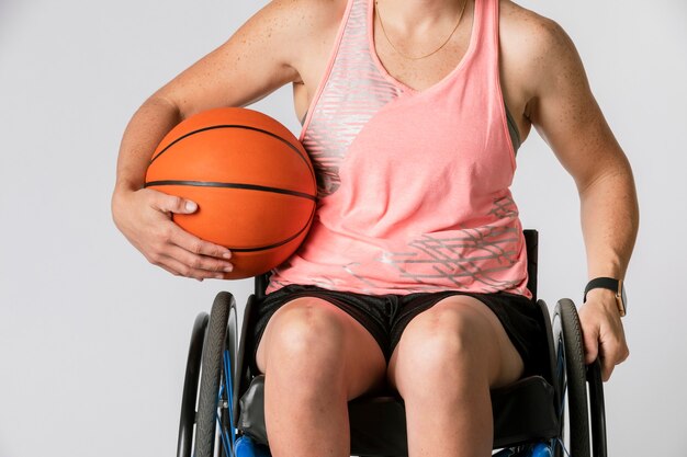 Atleta femminile in sedia a rotelle che tiene una palla da basket