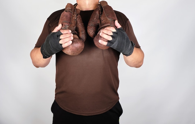 Atleta in abiti marroni tiene molto vecchi guanti da boxe in pelle vintage