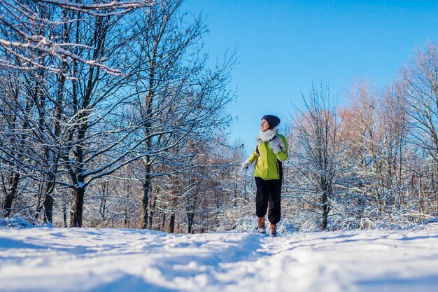Atleta in corsa donna sprint nella foresta invernale Allenamento all'aperto con tempo nevoso freddo