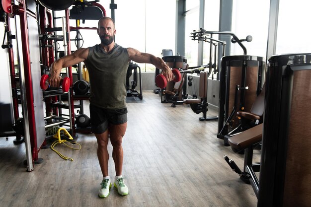 Atleta In Palestra Che Esercita La Spalla Con I Manubri