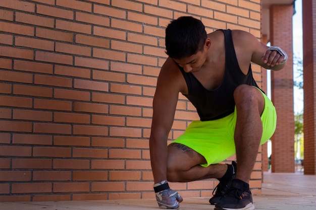 Atleta latino in stato di frustrazione in ginocchio che colpisce il suolo con il pugno mostrando rabbia e delusione
