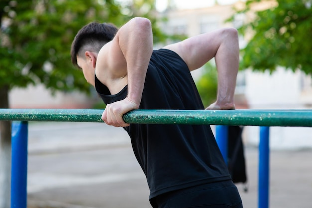 Atleta maschio che fa flessioni sulla vista posteriore delle barre irregolari