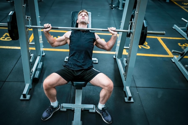 Atleta maschio che si esercita in palestra sollevando pesi tirando le articolazioni