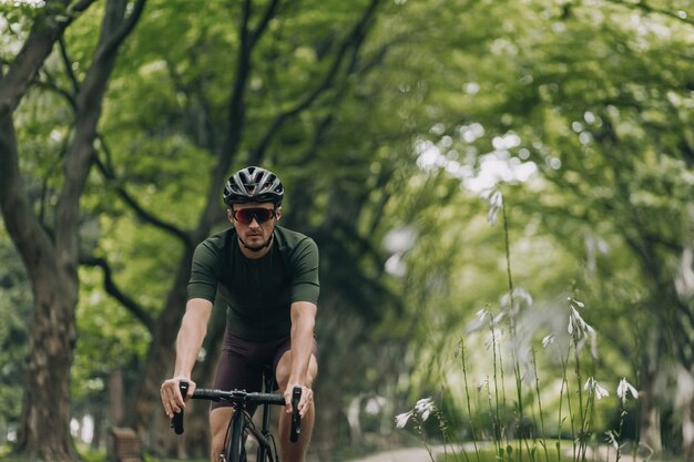 Atleta maschio in abiti sportivi che guidano la bici al parco estivo