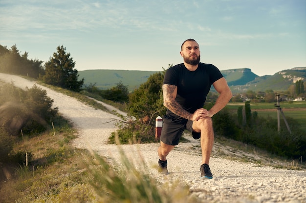 Atleta maschio in fase di riscaldamento prima di iniziare a correre in montagna