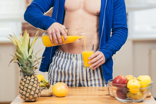 Atleta maschio prepara insalata e succhi di frutta fresca a casa in cucina