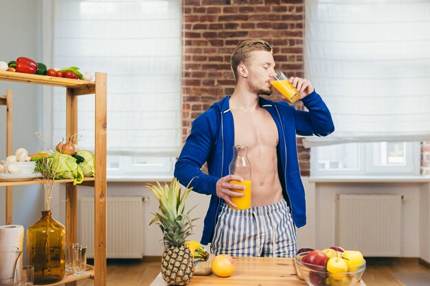 Atleta maschio prepara insalata e succhi di frutta fresca a casa in cucina