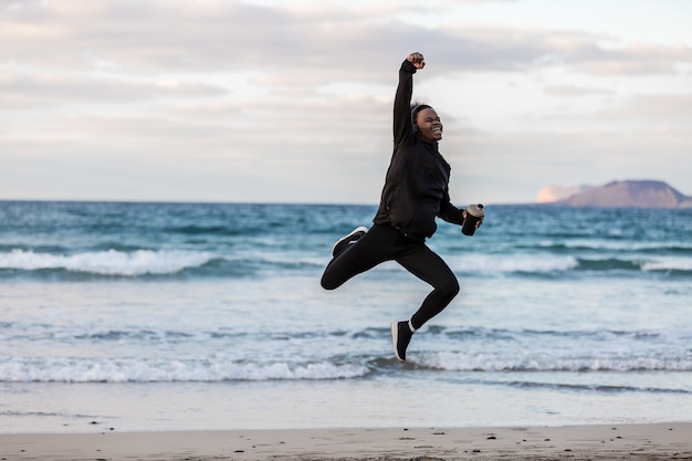 Atleta nero allegro che salta vicino al mare