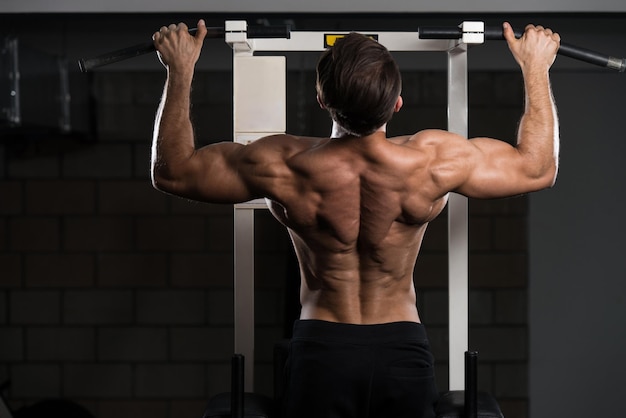 Atleta uomo bello che fa Pull Ups ChinUps in palestra