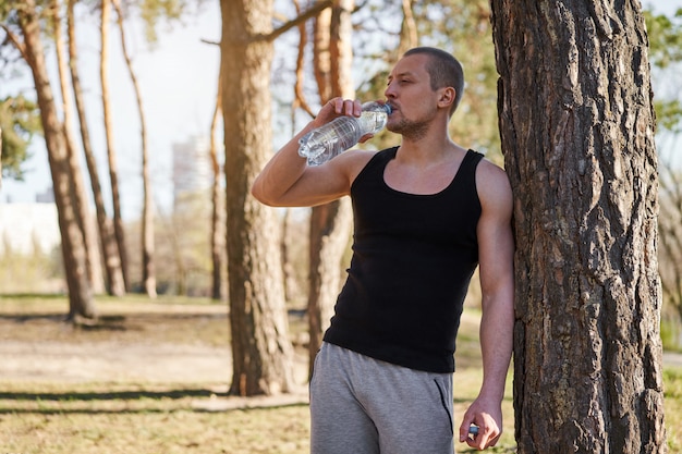 Atleta uomo bere acqua da una bottiglia di plastica