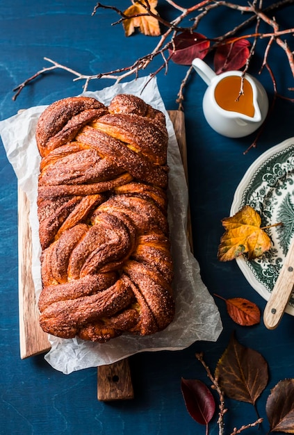 Atmosfera accogliente autunno ancora in vita con brioche di zucca e cannella su un tavolo blu vista dall'alto