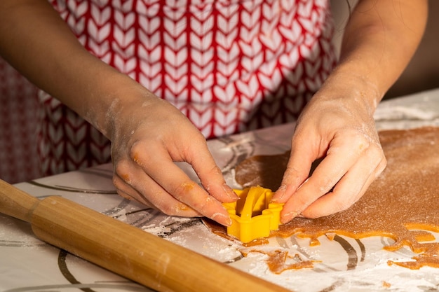 Atmosfera natalizia Le mani delle donne ritagliano forme con un motivo per la cucina casalinga dei biscotti